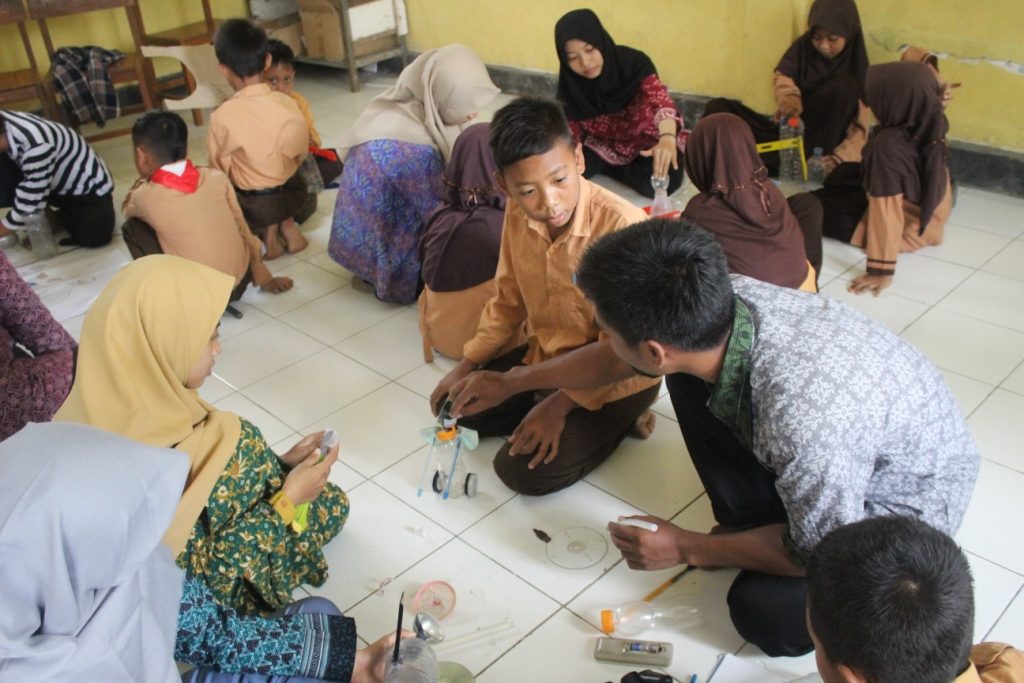 Dua mahasiswa UNAIR, Titik Nur Hayati alumnus Fakultas Vokasi (FV) dan Achmad Ardiansyah Romadhoni dari Fakultas Ilmu Sosial dan Ilmu Politik (FISIP) sedang mengajari pembuatan robot dari bahan bekas di kegiatan di Bhakti Jombang Chapter 7. (Foto: Fariz Ilham Rosyidi)
